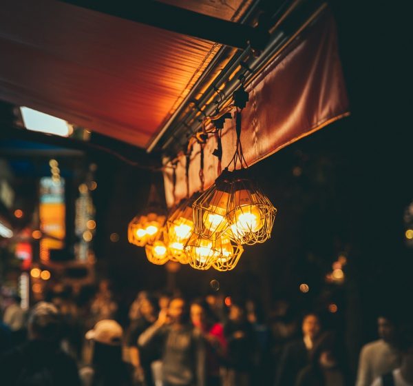 夜间室内环境中的手机屏幕，排盘 App 的对比视图并排显示两张命盘，中间用一条竖线分隔，屏幕映出微弱蓝光落在木质桌面上